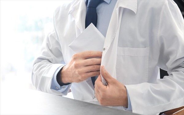 Γιατρός βάζει φακελάκι στην τσέπη της ποδιάς του