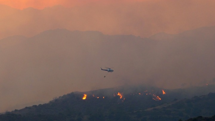 Φωτογραφία από μεγάλη πυρκαγιά που καίει δασική έκταση βόρεια της Λεμεσού, με πυροσβεστικό αεροπλάνο στον ουρανό
