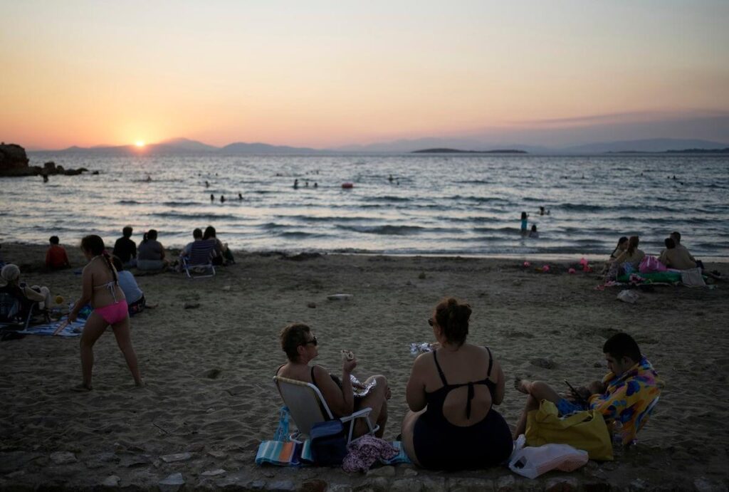 Οικογένεια στην παραλία με τάπερ και ομπρέλα από το σπίτι