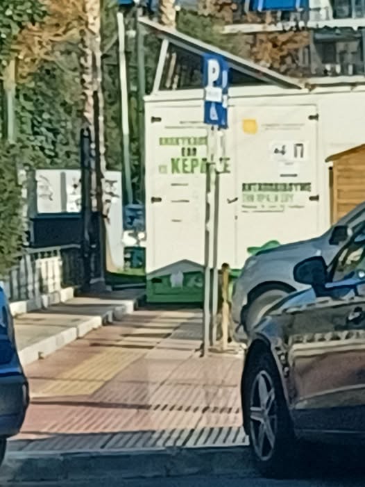 Πασαλιμάνι: σπιτάκι ανακύκλωσης τοποθετημένο πάνω στον οδηγό όδευσης τυφλών κάτω από το ρολόι